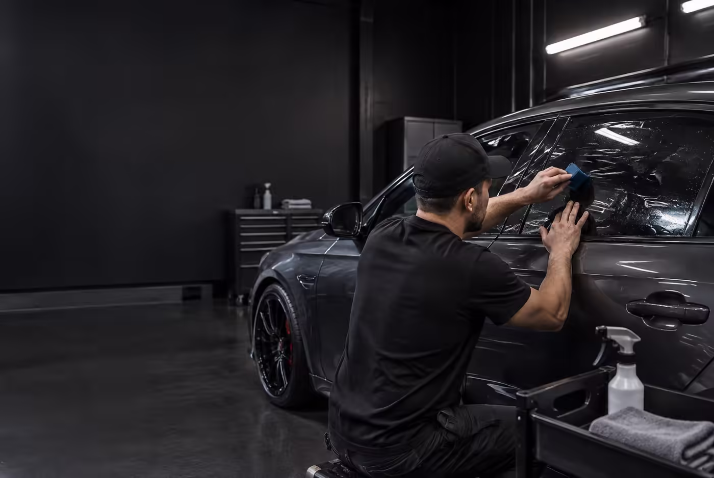 Installer carefully applying ceramic film to a sedan window